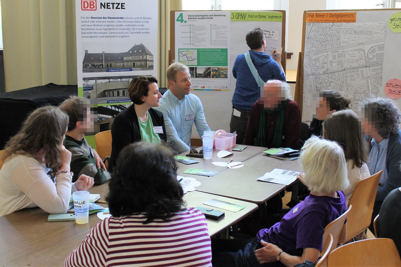 Bürgerinnen im Dialog mit dem Projektteam, im Hintergrund Infoplakate und Pläne